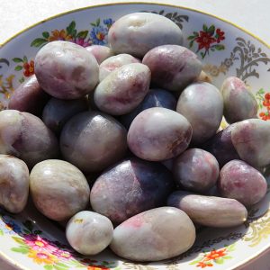 Purple and white gemstone pebbles in a bowl.