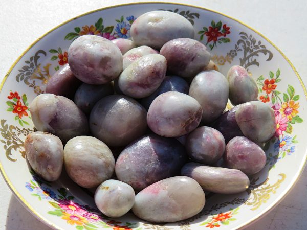 Purple and white gemstone pebbles in a bowl.