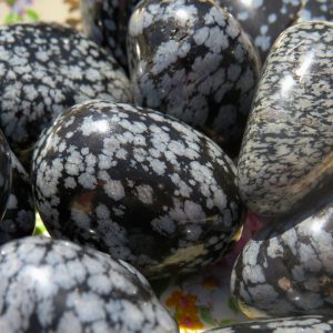 Polished snowflake obsidian stones on a plate.