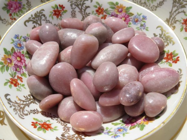 Pink tumbled stones on a floral plate.