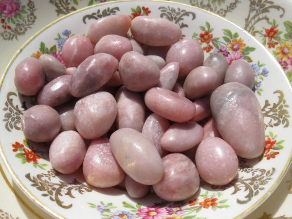 Pink tumbled stones on a floral plate.