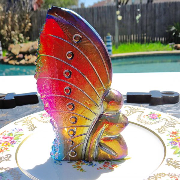 Rainbow iridescent glass butterfly on plate.