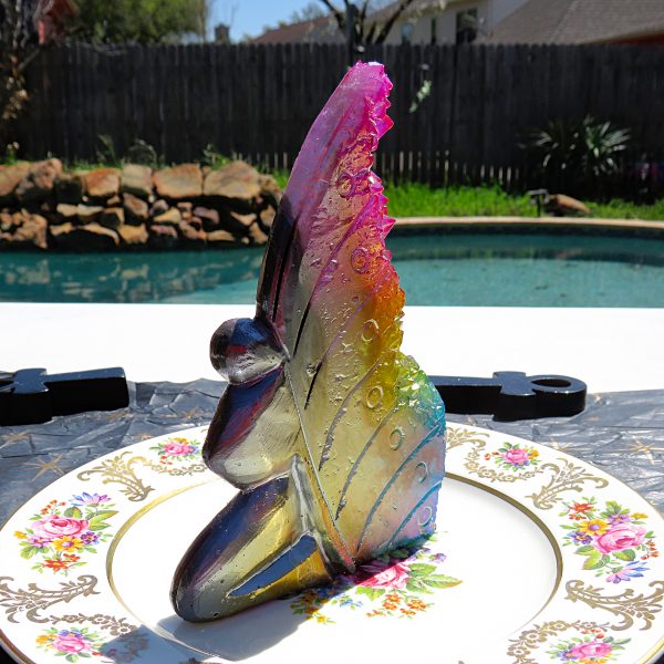 Rainbow glass fairy figurine on a plate.