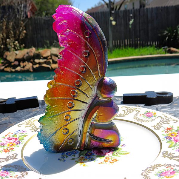 Iridescent glass butterfly on a plate.