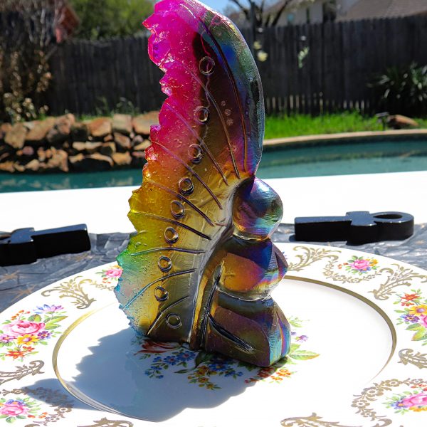 Iridescent glass butterfly figurine on plate.
