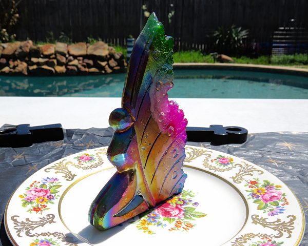 Iridescent glass fairy figurine on plate.