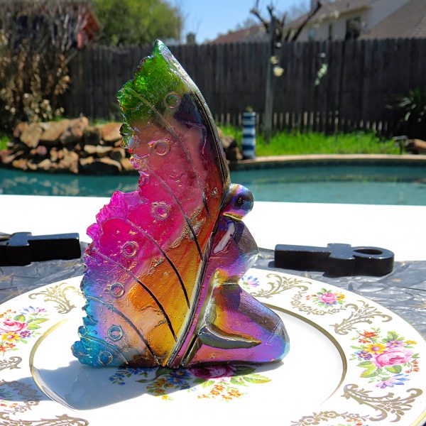 Iridescent glass butterfly figurine on plate.