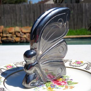 Silver butterfly figurine on floral plate.