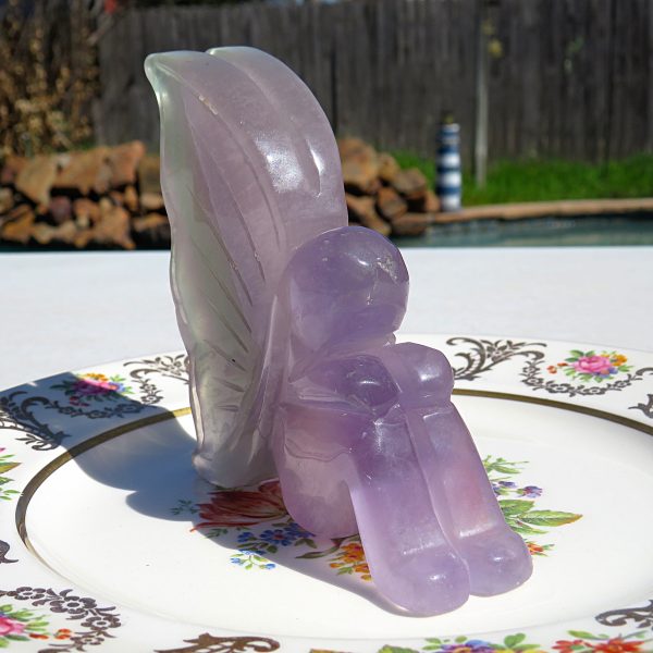Purple amethyst carved fairy figurine on plate.