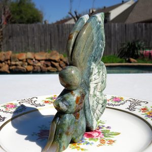 Green stone butterfly figurine on plate.