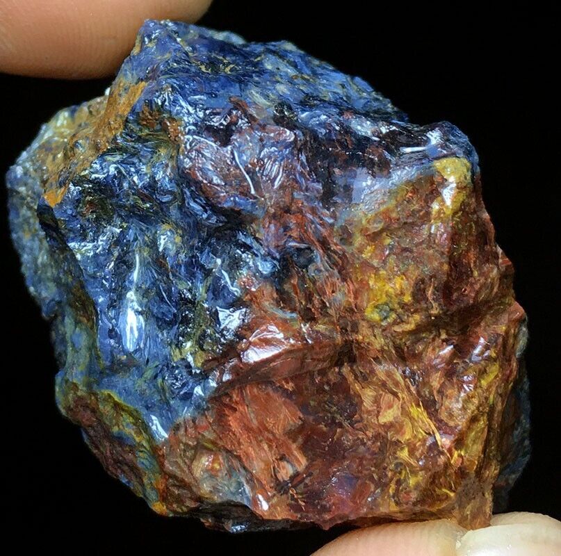 A person holding a piece of blue and yellow rock.