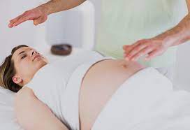 A pregnant woman being massaged by a man image in color