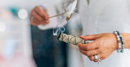 A woman is holding a stick of incense in her hand image