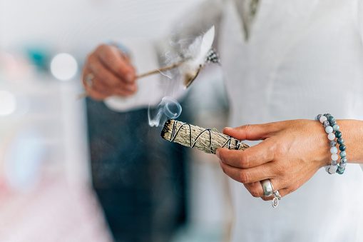 A woman is holding a stick of incense in her hand image