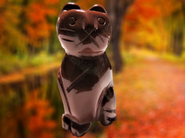Carved obsidian cat figurine in autumn.