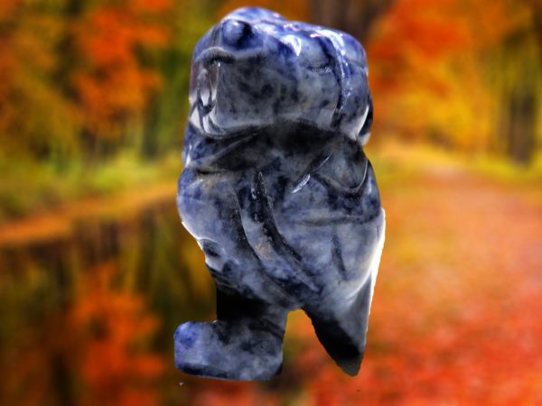 Blue carved stone figurine in fall foliage.