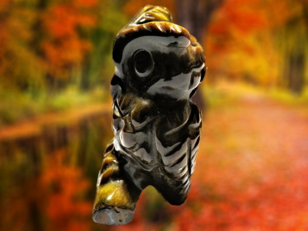 Carved owl figurine against fall foliage.