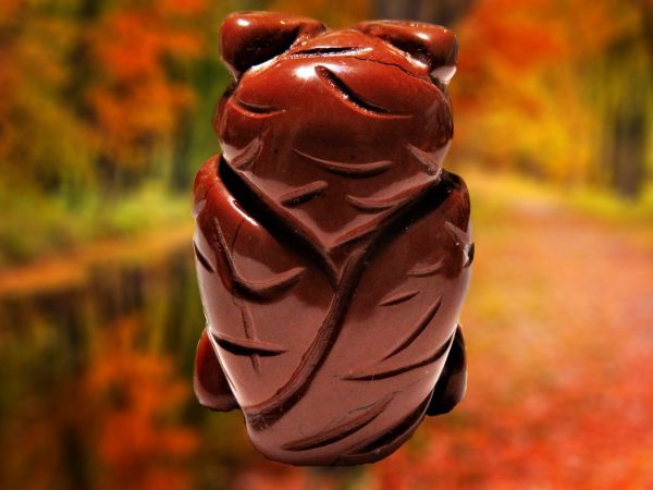 Red carved owl figurine on autumn background.