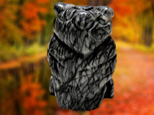 Stone owl carving against fall foliage.