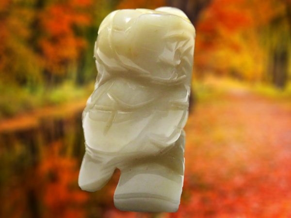 White carved owl figurine on fall background.