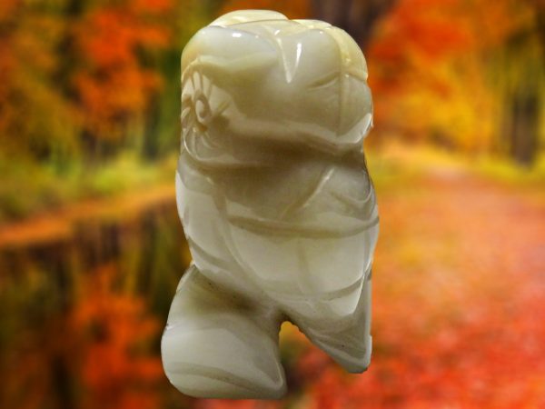 White carved owl figurine on blurred background.