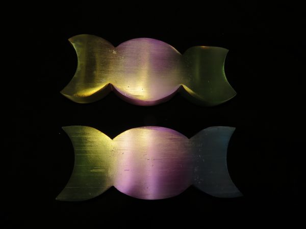 Two iridescent crescent shapes on black.