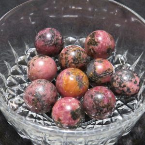 Pink and black gemstone spheres in a bowl.