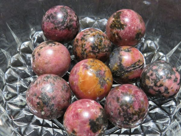 Pink and black marble spheres in bowl.