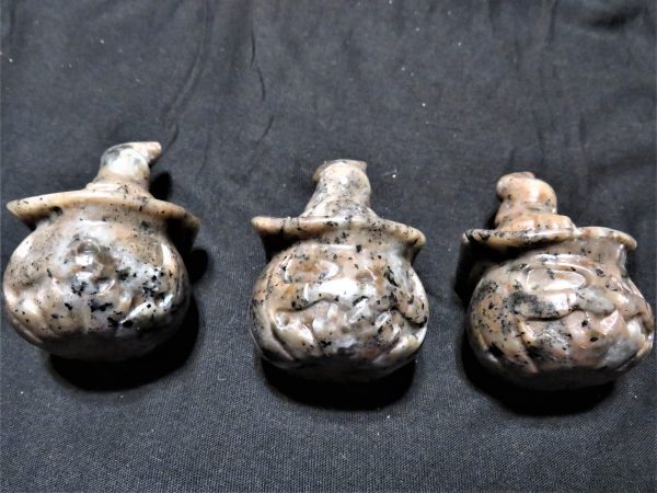 Three carved stone pumpkin figures.