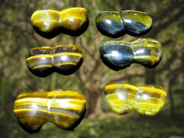 Six tiger eye stones on a green background.