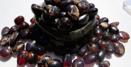 A bowl of black and brown beans on top of a white surface.