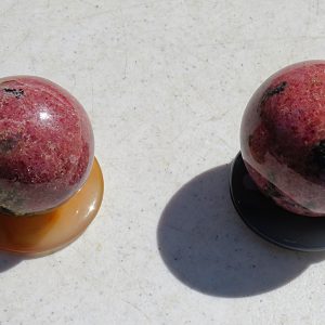 Two pink and black gemstone spheres on stands.