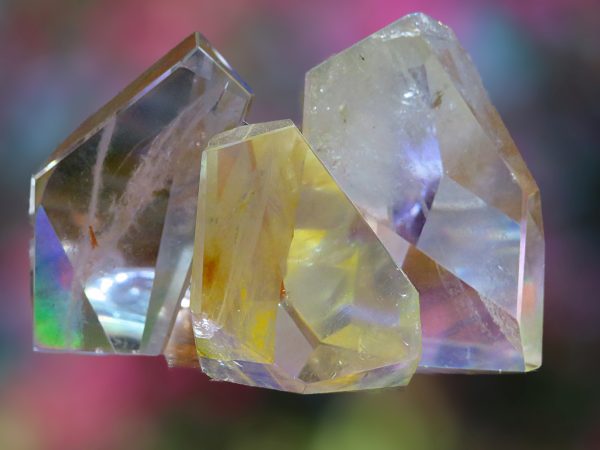 Three clear iridescent crystals on blur background.