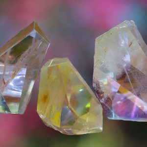 Three iridescent crystals on a blurred background.