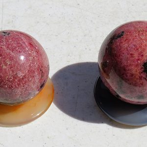 Two red and black gemstone spheres on bases.