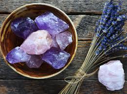 A bowl of crystals and lavender on a wooden table.