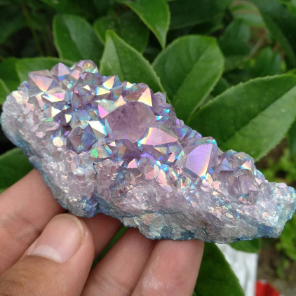 A person holding a rock with purple crystals on it.