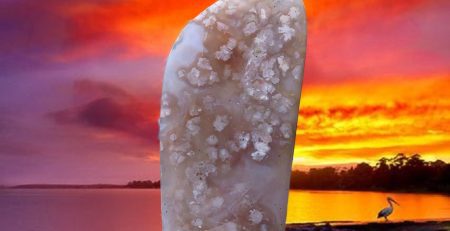 A large piece of jade sitting on a rock in front of a sunset.