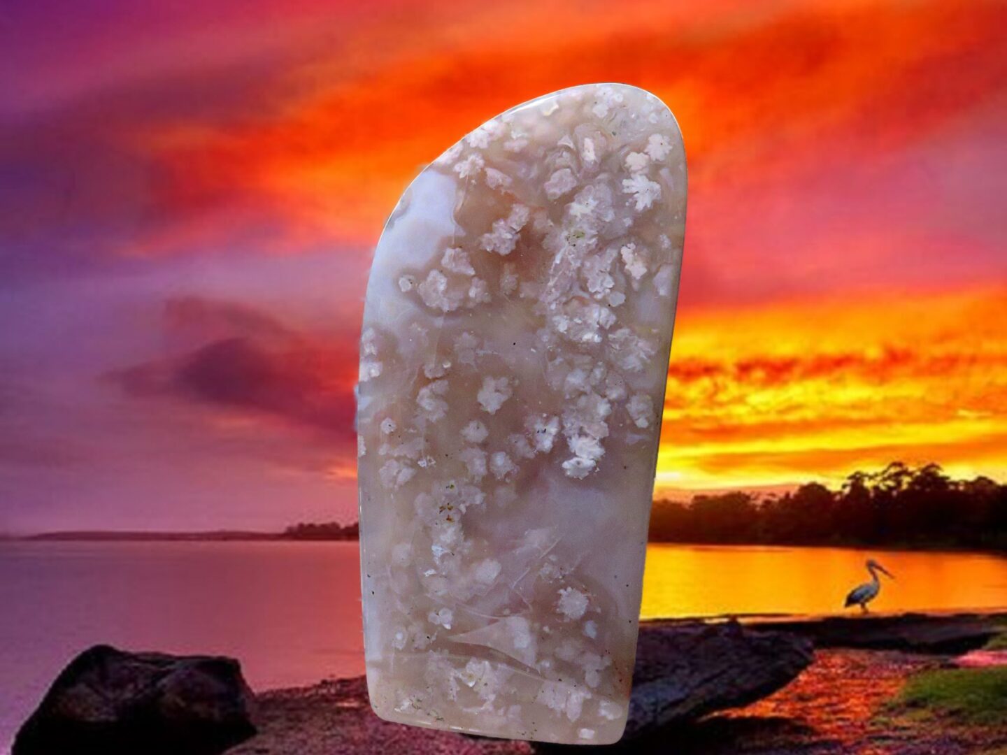 A large piece of jade sitting on a rock in front of a sunset.